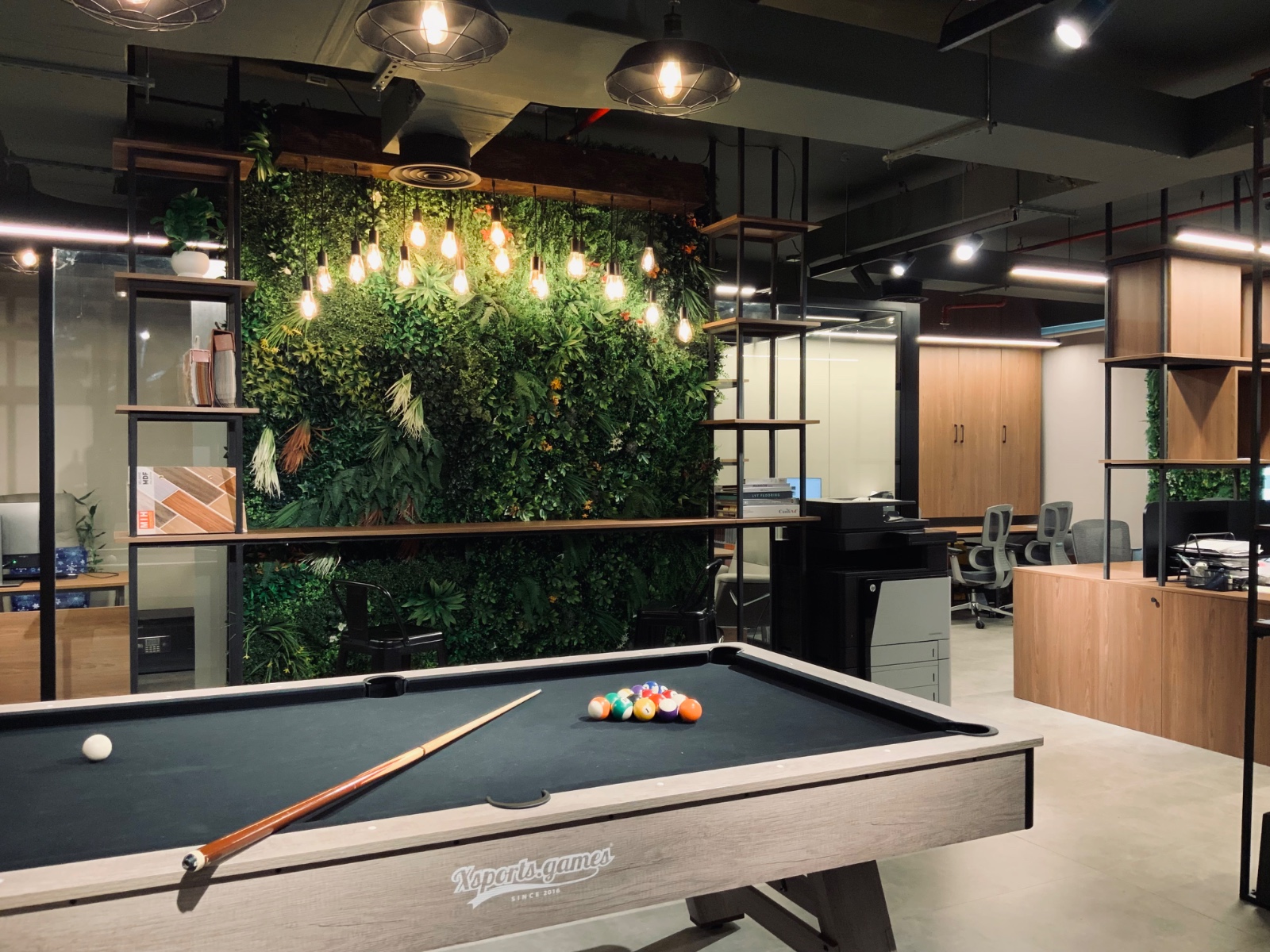 Interior design in Abu Dhabi featuring a living green wall, warm pendant lighting and bespoke wooden shelving